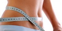 Close up of a slim waist with measuring tape.